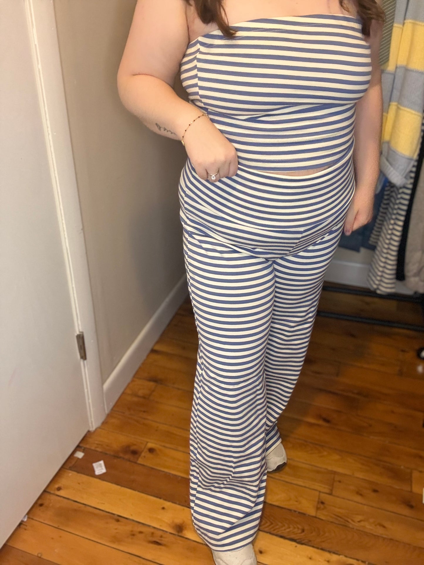 Person wearing a blue and white striped outfit standing in a room with wooden flooring.