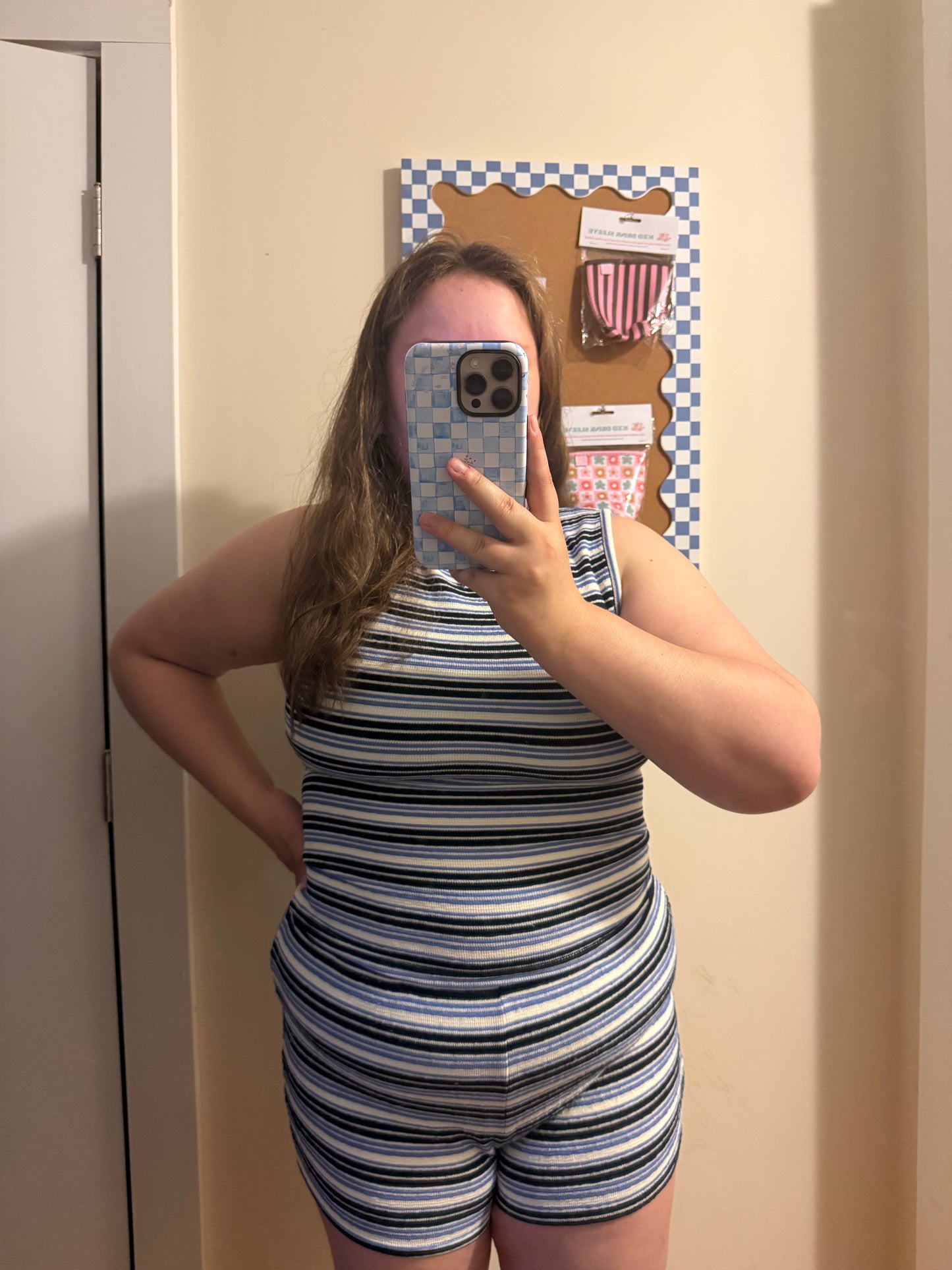 Person wearing a striped romper taking a mirror selfie.