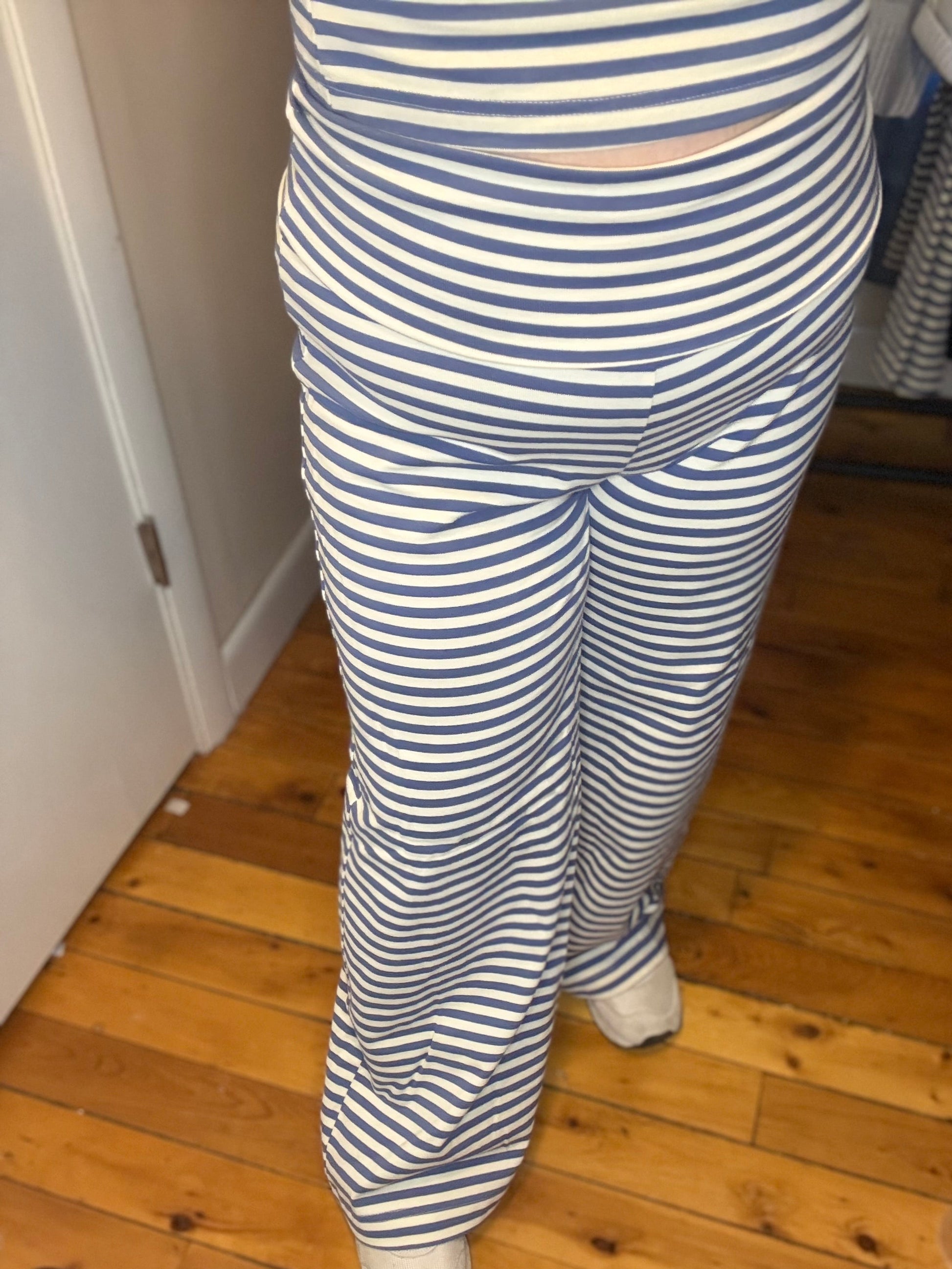 Person wearing blue and white striped pants on a wooden floor.