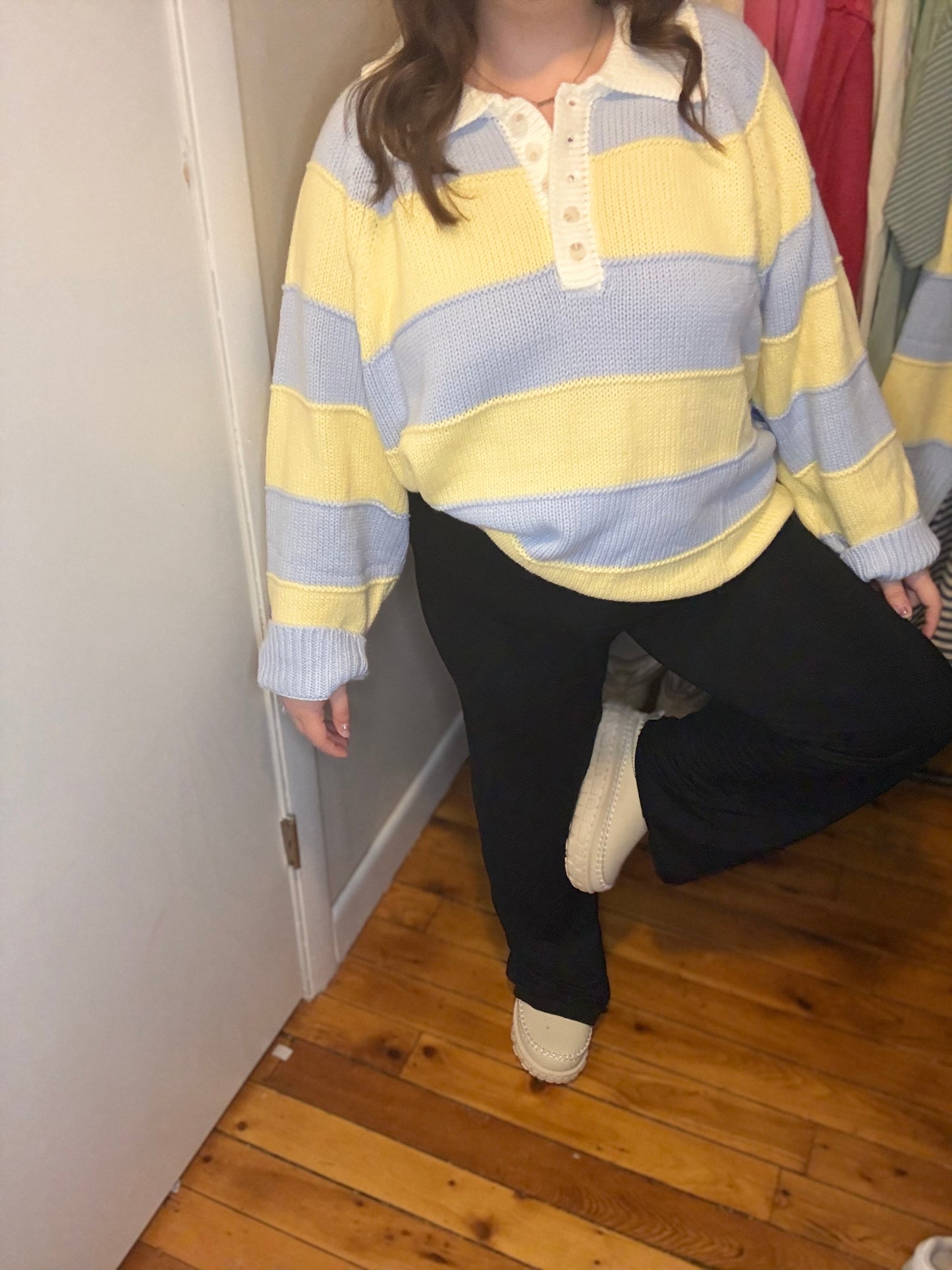 Person wearing a yellow and blue striped sweater in a room with wooden flooring.
