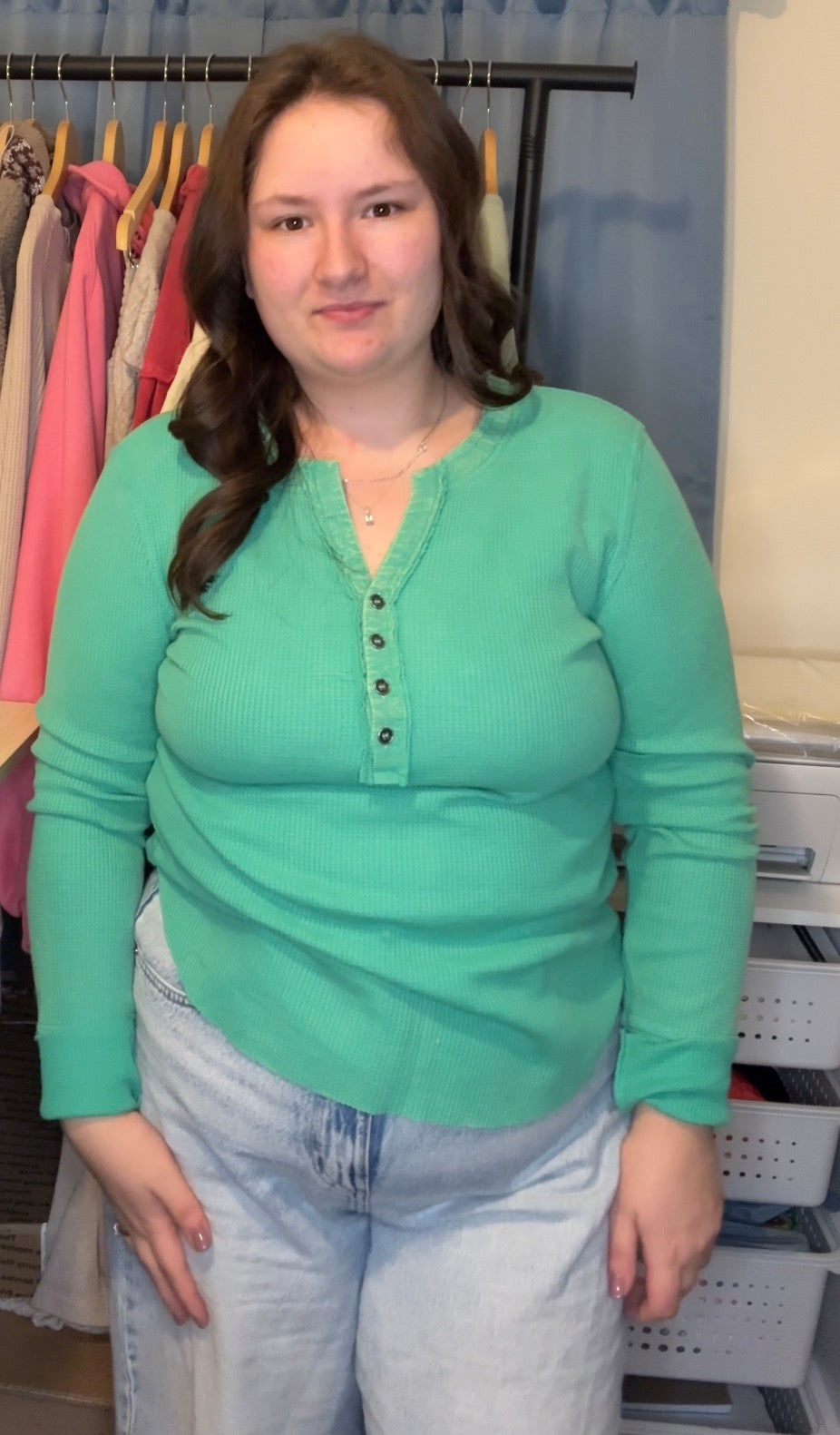 Woman wearing a green shirt standing in a clothing store.