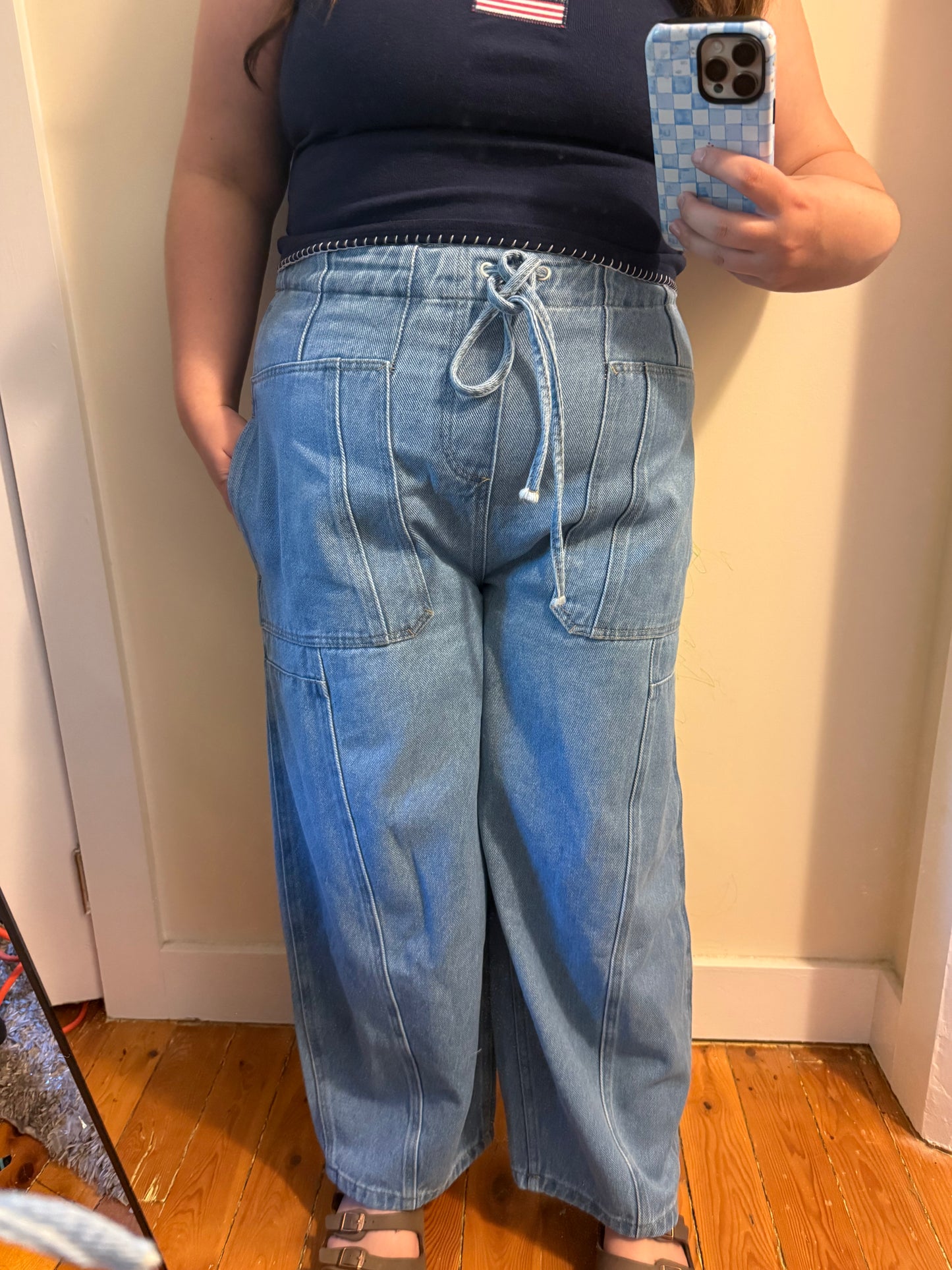 Person wearing blue jeans and a navy top, taking a mirror selfie.